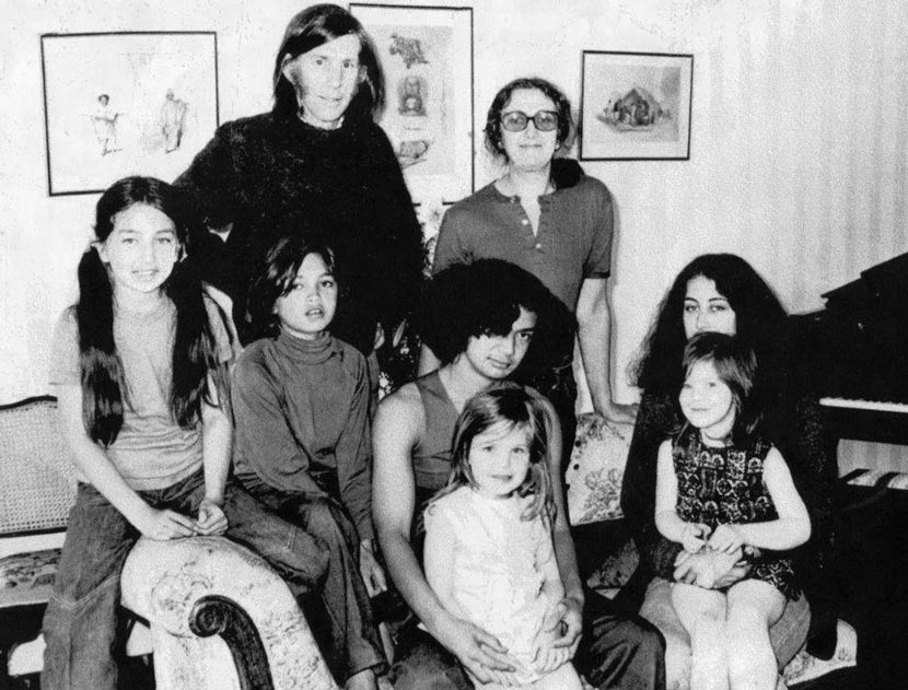A middle-aged couple standing behind six seated children, ranging in age from schoolchildren to teenagers. 