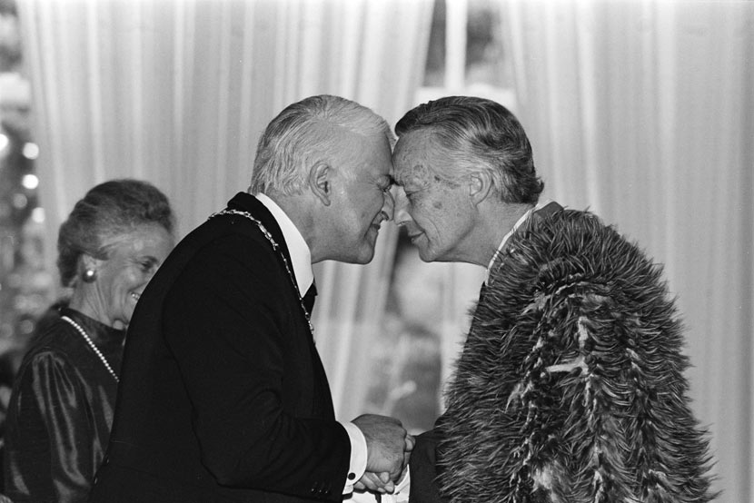 A profile photograph showing Reeves and Kawharu engaged in a hōngi (pressing noses together in greeting). Kawharu wears a kahukiwi (Māori cloak of kiwi feathers).