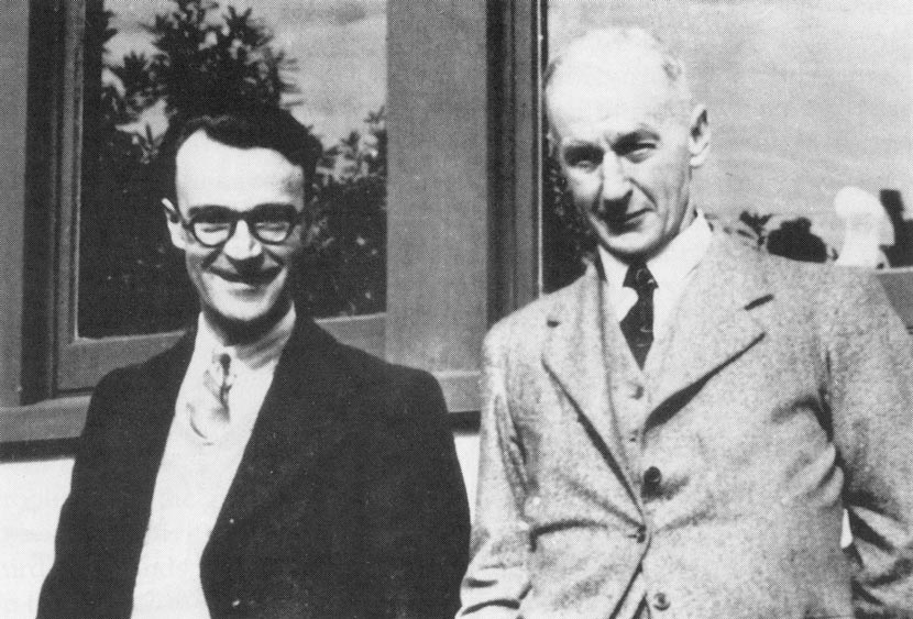 Two men in suit jackets standing side by side. 