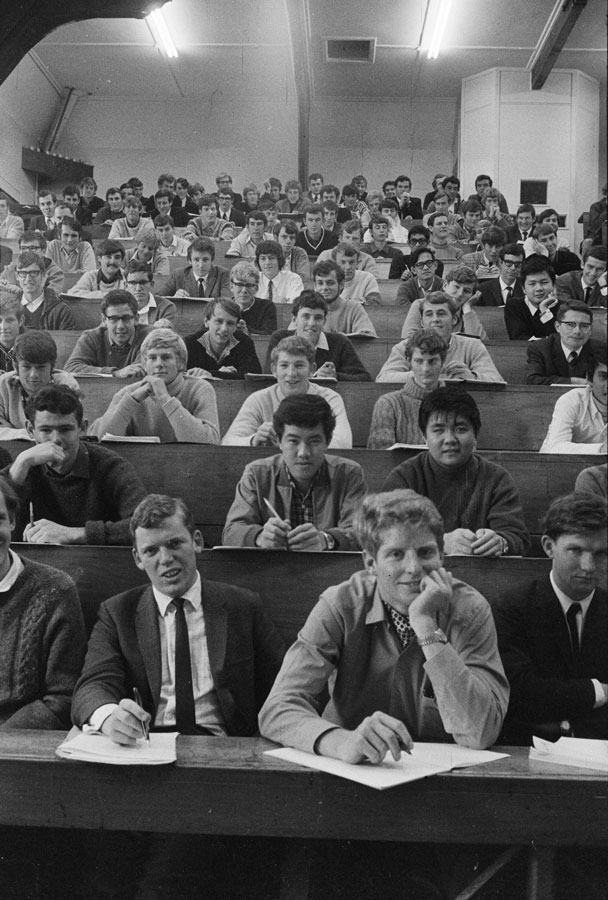 A roomful of university students sitting in tiered seats in a lecture theatre.