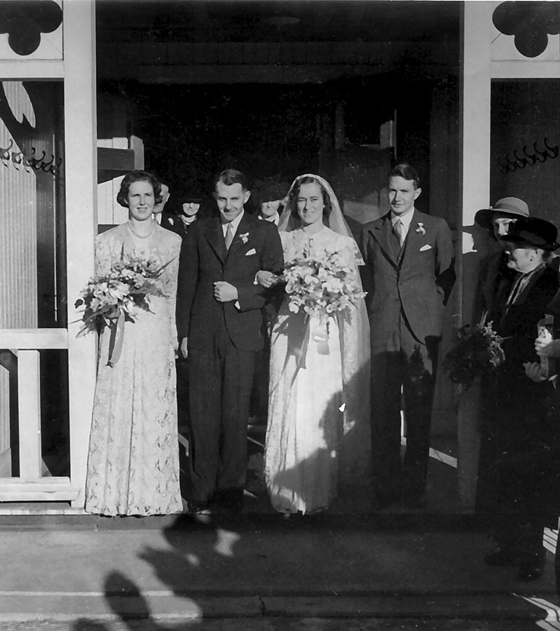 Owen Woodhouse and Peggy Thorpe, wearing wedding outfits, stand in a church doorway, surrounded by friends and family.