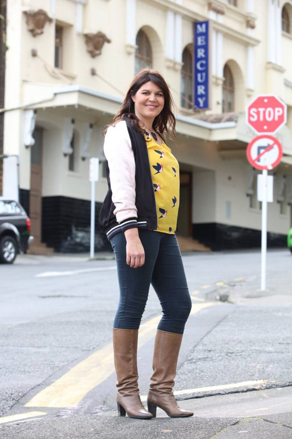 Woman standing on a road smiling at the camera.