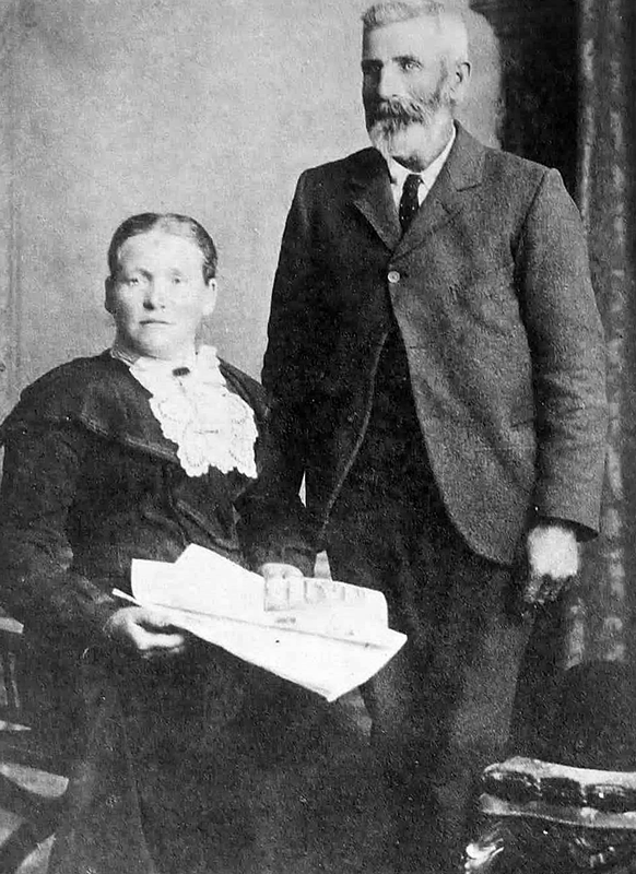 Woman sitting holding papers with a man standing next to her in suit and tie