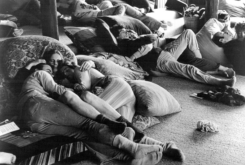 People lying on a carpeted floor, cuddled up on beanbags.