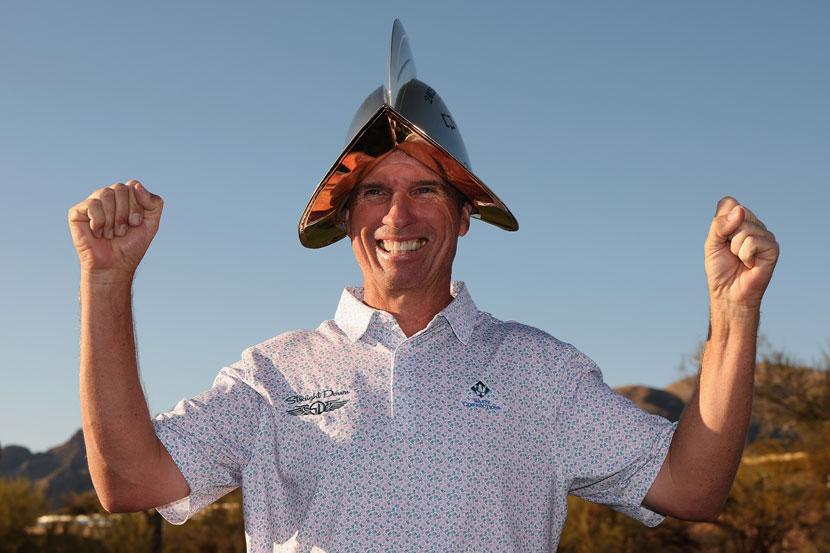 Smiling man with arms raised wearing trophy as a hat
