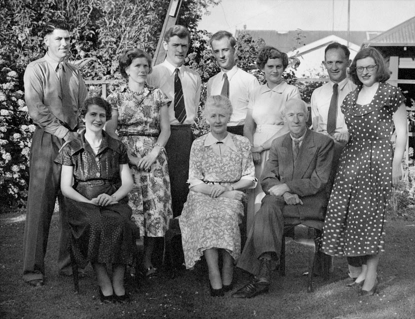 A group of adults posed outdoors, seven standing and three seated. 