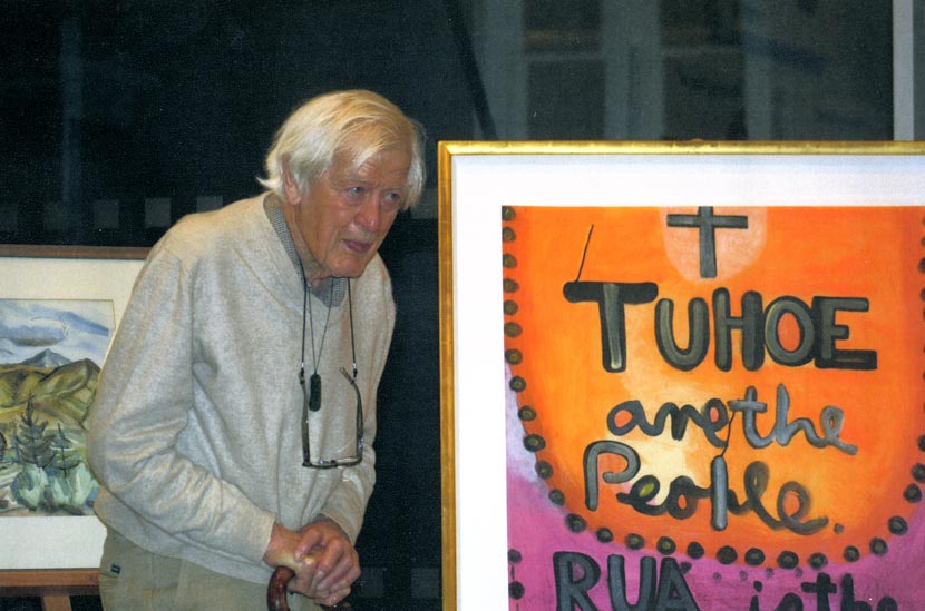 A man standing in front of two paintings.