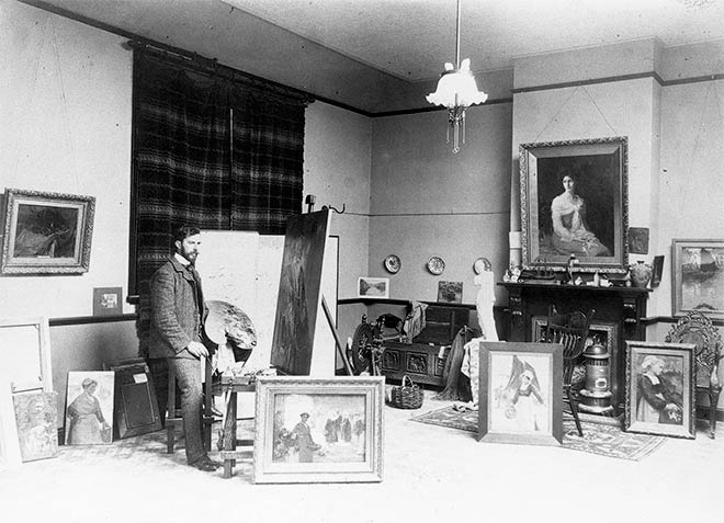 Sydney Lough Thompson at his easel surrounded by his works, probably after 1905