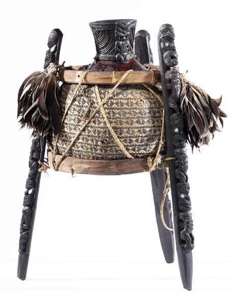 Gourd container (taha huahua) on carved wooden stand decorated with bird feathers.