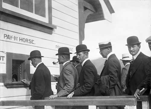 Queue of men in top hats outside horse betting booth