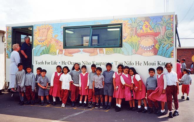 Children lined up in front of mobile dental health van