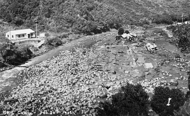 A devastated landscape with broken buildings and river debris.