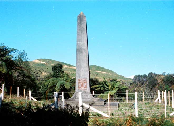 A tall concrete obelisk memorial surrounded by a fence.