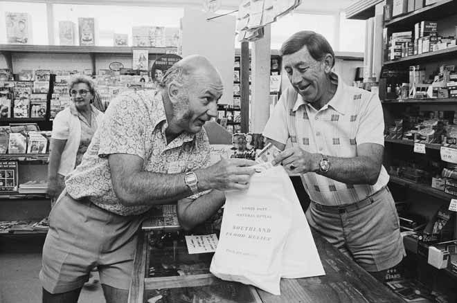 People standing in a shop with bags labelled ‘Southland Flood Relief’.