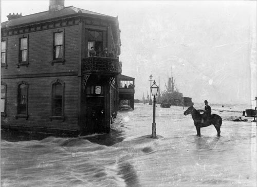A man on a horse standing in flood waters in front of a hotel.