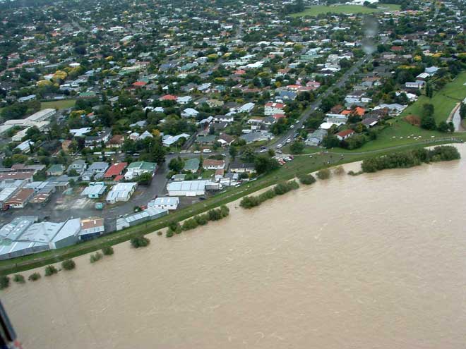 A river in flood beside a city suburb. 