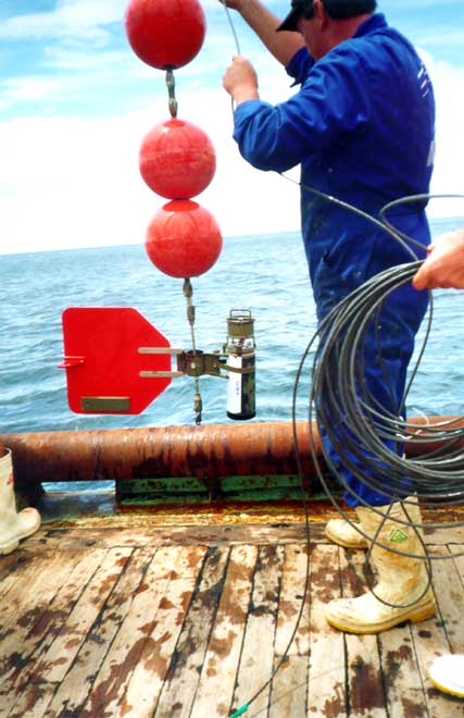 Man lowering scientific equipment with buoys from boat 