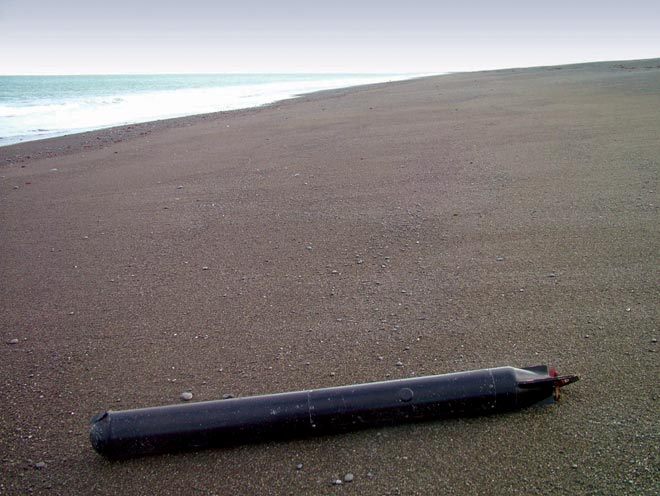 Black metallic cylinder on beach