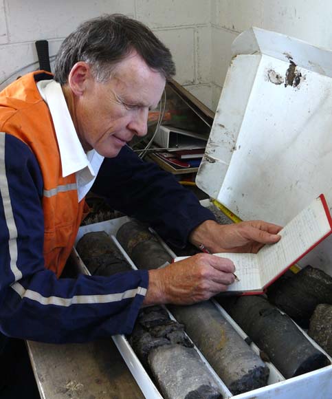 Man leaning on core samples making notes in notebook