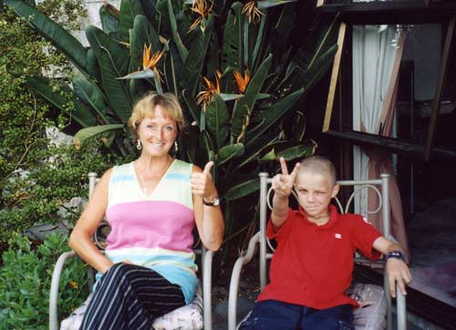 Woman with thumb up and boy with fingers in peace sign on deck chairs