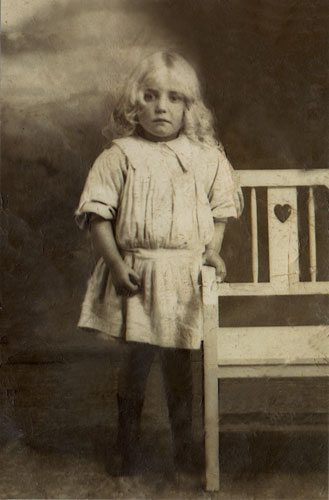 Young girl standing next to a chair