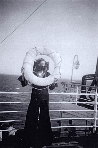 Women in mask and cape looking through life-saving ring on board a ship