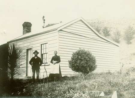 Man and woman in front of small wooden cottage