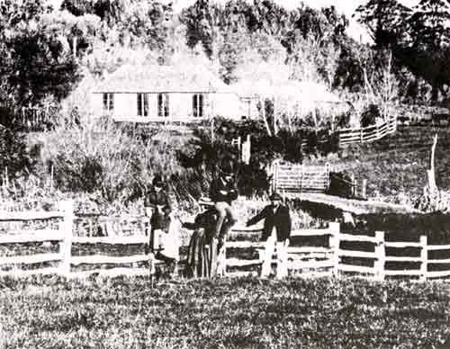 Family group in front of wooden fence with large house in background