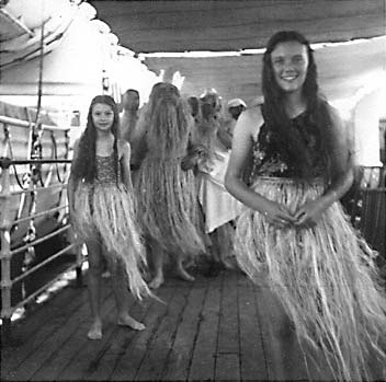 Young women in grass skirts on ship