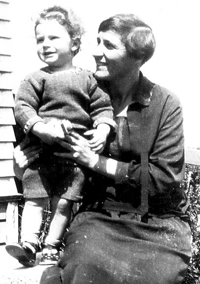 Mother sitting supporting a child standing next to her