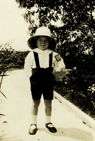 Young boy with large hat standing on path