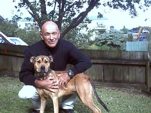 Man in back yard crouched holding his dog