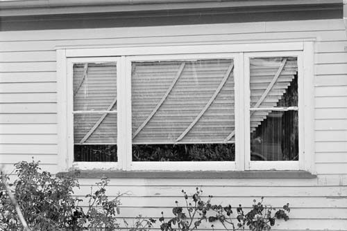 Window in wooden house with blinds pushed to one side