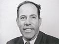 A head and shoulders portrait of a middle-aged man in a suit and tie.