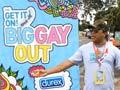 A man stands in front of a Big Gay Out poster