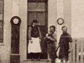 Three men standing next to clock outside building