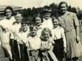 Seven school kids and two teachers posing for photograph in paddock
