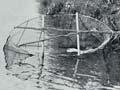 A man submerges a net in the water on the edge of a riverbank