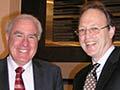 Two men in suits drinking wine and laughing 