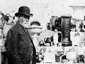  Luke Adams with examples of his firm's pottery at a show, 1897