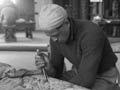 Pineāmine Taiapa working on a wood carving with a chisel