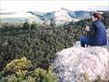 Woman sitting on a rock overlooking a bushy valley below