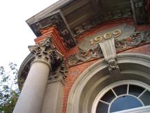 Front of old brick building with arched window and '1909' plaque