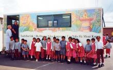 Children lined up in front of mobile dental health van