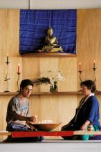 Man and women in sitting cross-legged at Buddhist shrine