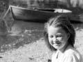 Girl sitting on a beach with dingy moored in background