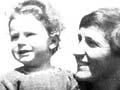 Mother sitting supporting a child standing next to her