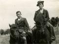 Boy and older girl sitting on horse back on farm track