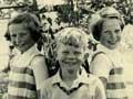Boy with a girl on each side leaning against a tree