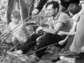 Cooking sausages over an open fire, Cable Bay, 1970